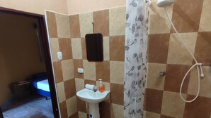 A bathroom with a toilet, sink, shower, and patterned floor tiles. - La Casa Colorada (San Benito)