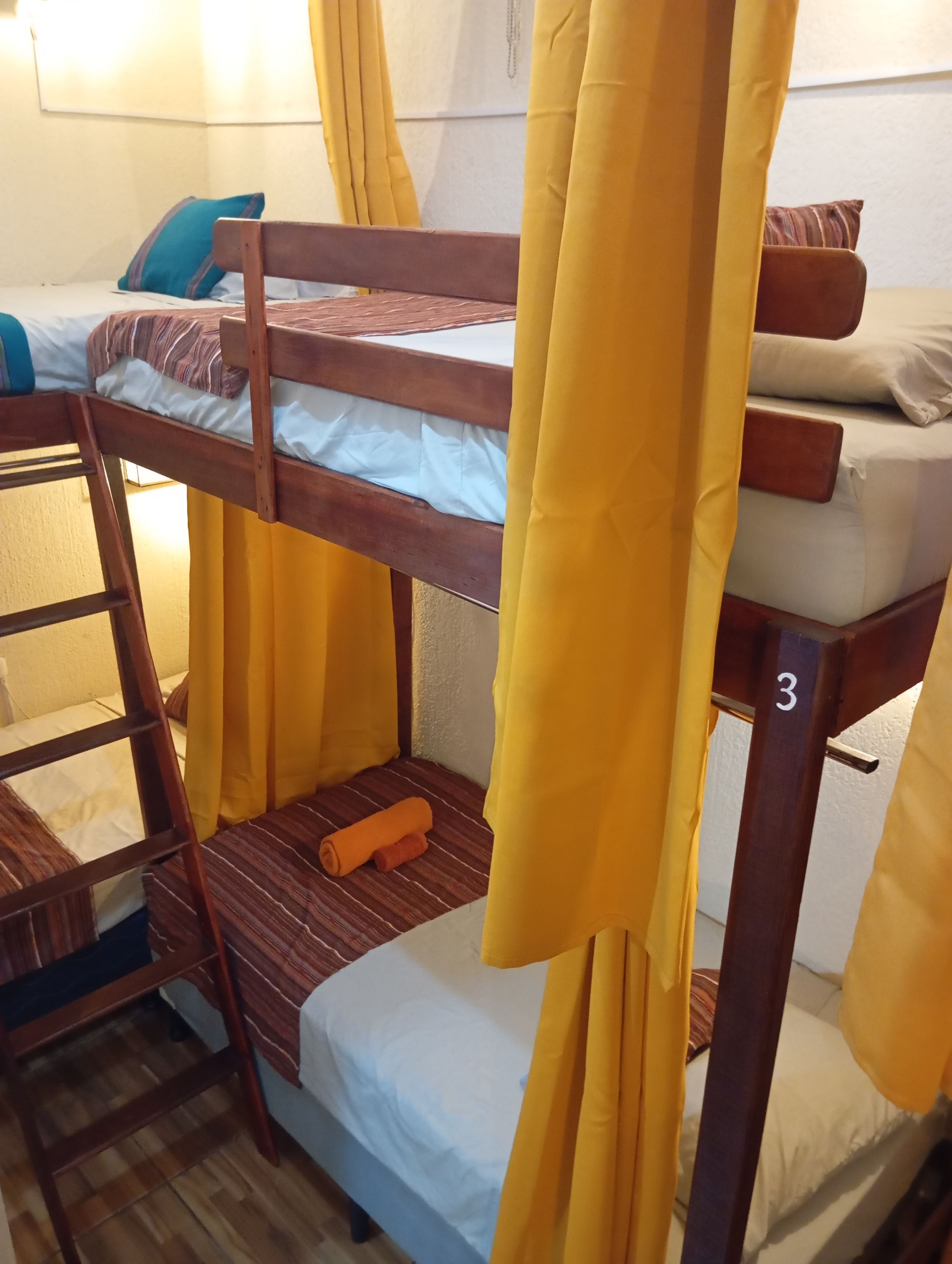 A bunk bed with a wooden ladder, a number '3' on the side, and yellow curtains.