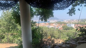 A balcony with a view of a cityscape, a white column, and a stone wall.