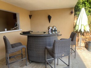 An outdoor dining area with a round table and four wicker chairs. - Room for rent with shower and summer kitchen in a lush, green setting with a pool (La Seyne-sur-Mer)