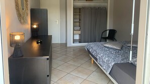 A bedroom with a bed, bedside table, lamp, wardrobe, and a chair.