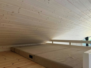 A room with a sloped ceiling and a wooden floor.