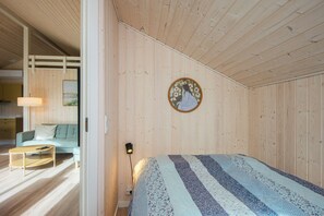 Et værelse med en seng, en sofa, et lille bord og en lampe på væggen.