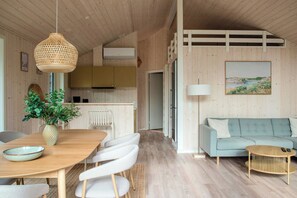 Et moderne interiør med et træspisebord, stole, en sofa og et køkkenområde.