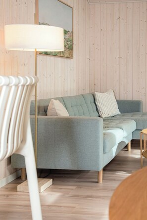 En moderne stue med en grå sofa, en hvid stol og en gulvlampe.