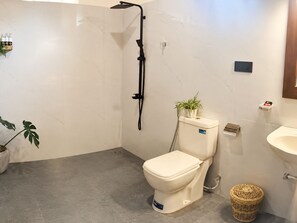 Ein Badezimmer mit Toilette, Dusche, Waschbecken und einem Blumentopf.