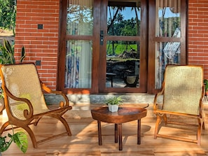 A brick exterior with a glass door and windows, two wicker chairs, a small round table, and a potted plant. - Private Pool Villa (Tangalle)