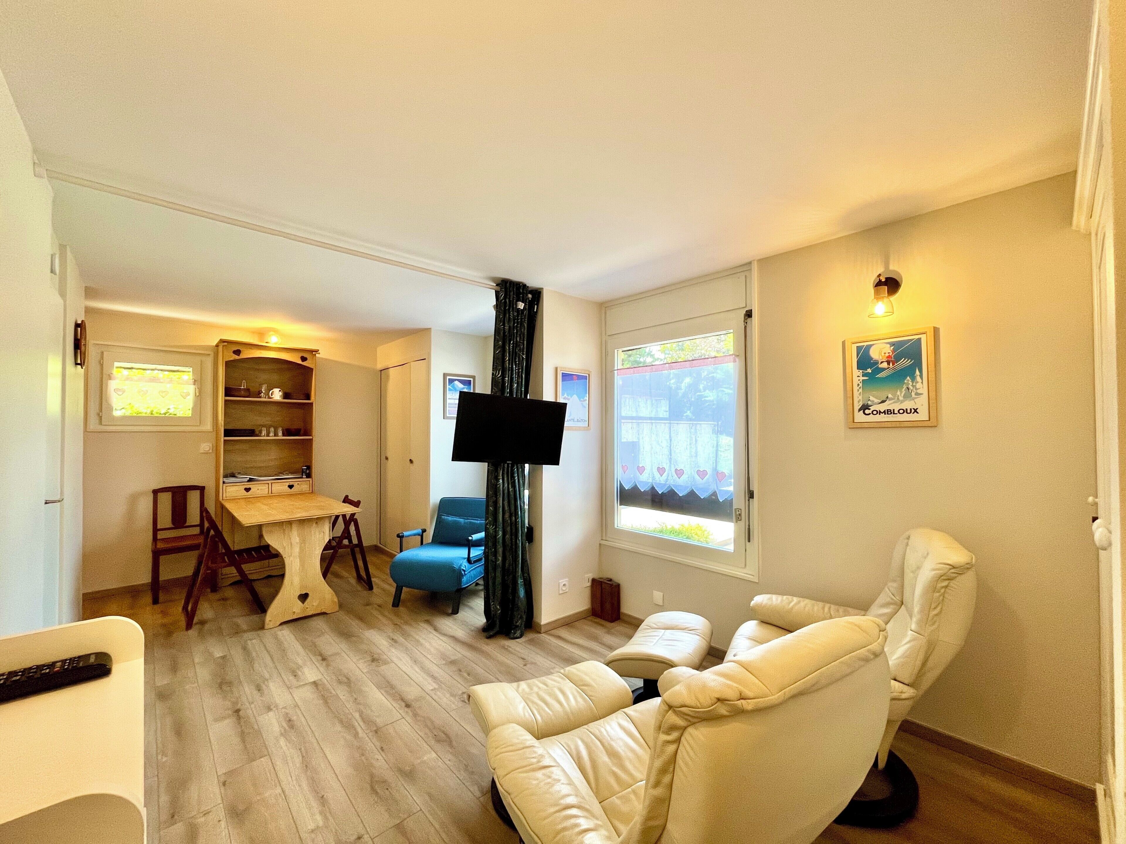 A living room with a sofa, a TV, a blue chair, a wooden table, and a bookshelf.