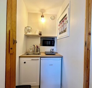 Una kitchenette compacta equipada con microondas, cafetera y lavavajillas Bosch.