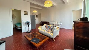 Uma sala de estar com sofá, mesa de centro e um espaço de jantar com cadeiras.