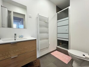 A bathroom with a white sink, wooden vanity, a towel rack, a toilet, and a shower area. - Newly renovated apart in the heart of Old Antibes (Antibes)