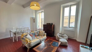 Uma sala de estar com sofá, cadeiras, mesa de centro e uma janela grande.