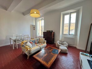 Ein Wohnzimmer mit einer Couch, Sesseln, einem Couchtisch und einem großen Fenster.