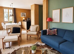A cozy living room with a blue sofa, two armchairs, a dining table with chairs, a kitchen area, and framed artwork on the wall. - Spacious and bright with balcony & Mont Blanc view (Chamonix-Mont-Blanc)