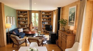 A cozy living room with a blue sofa, a round coffee table, and a bookshelf filled with books. - Spacious and bright with balcony & Mont Blanc view (Chamonix-Mont-Blanc)