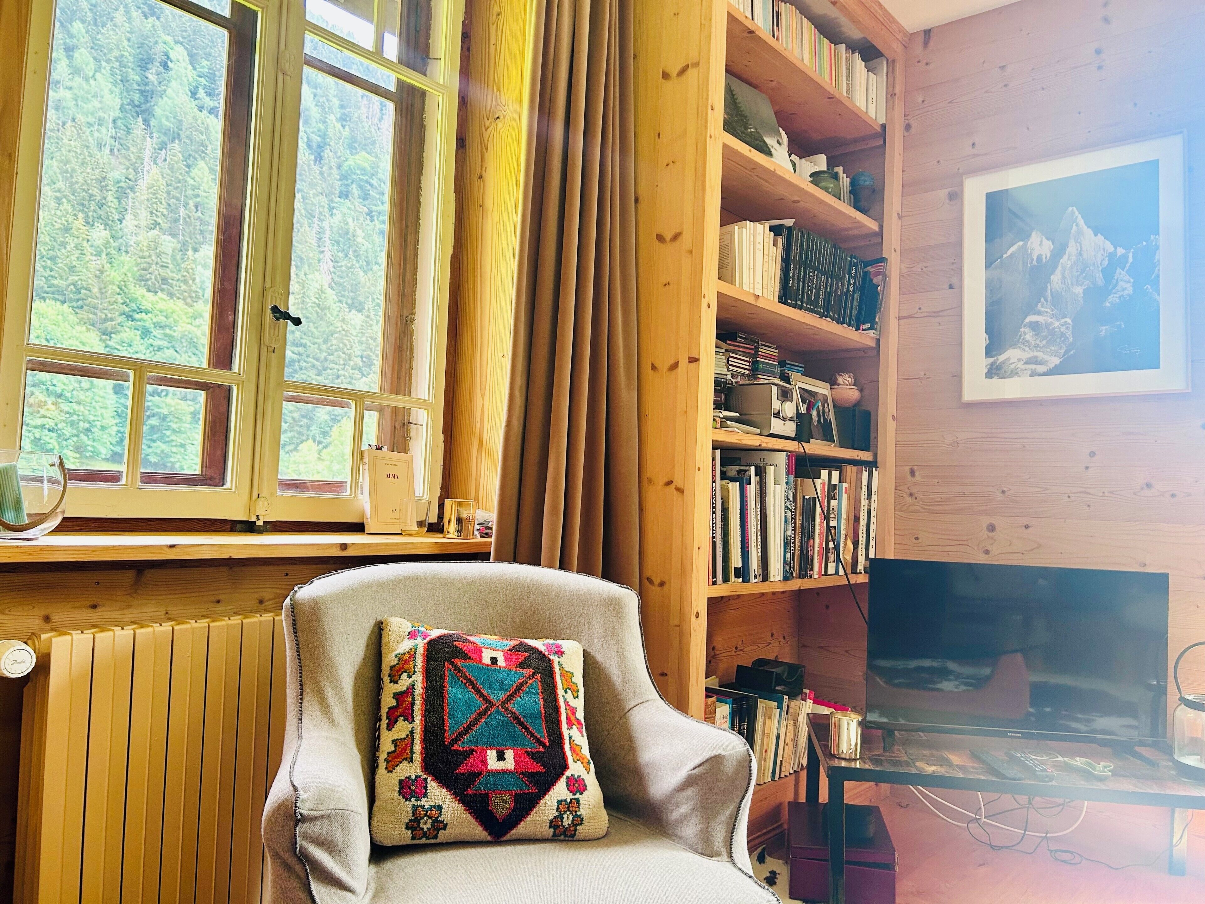 A cozy room with a wooden bookshelf, a comfortable armchair, and a television.