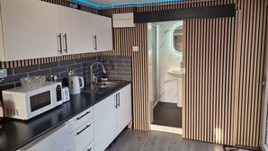 Une cuisine moderne avec des meubles blancs, un plan de travail noir et un four à micro-ondes.