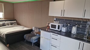 Une chambre moderne avec un lit, une table de chevet et un petit coin salon.