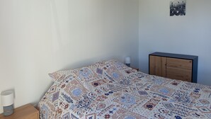 Ein Schlafzimmer mit einem Bett, einem Nachttisch, einer Lampe, einem Holzschrank und einer Wanddekoration.
