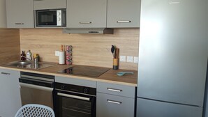 Eine moderne Küche mit grauen Schränken, einem Edelstahlkühlschrank, einer Mikrowelle und einem Geschirrspüler.