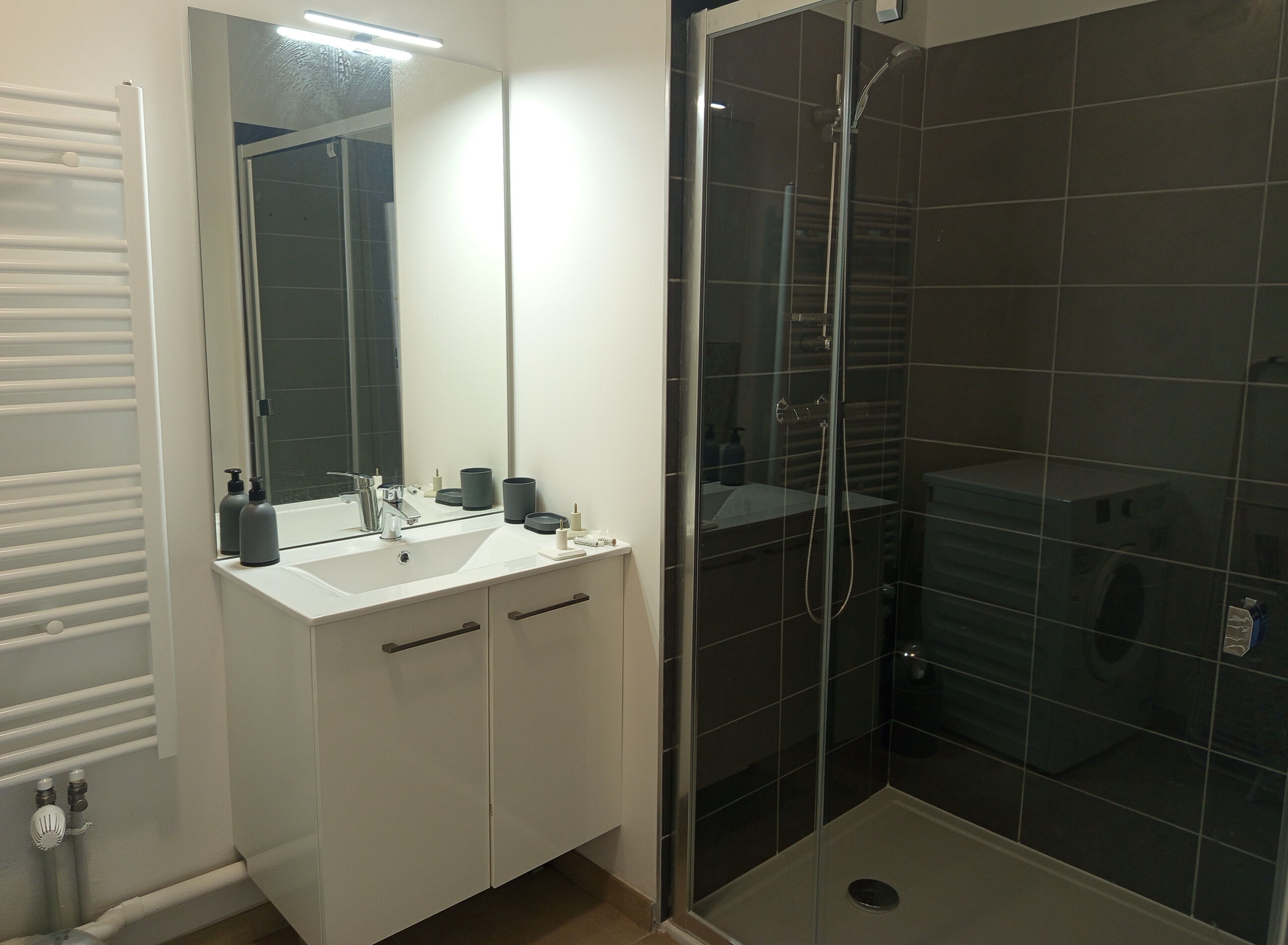 A bathroom with a white sink, mirror, and a glass-enclosed shower.