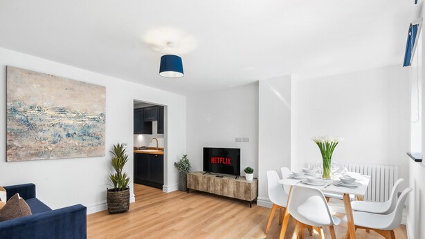 A modern living room with a TV, dining area, and a large abstract painting. - Urban Breeze By My Getaways (Brighton)