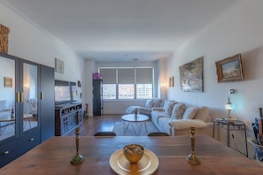 Una sala de estar moderna con comedor, ventanas grandes y vista a la ciudad.