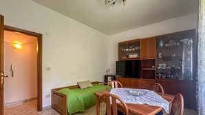 A compact room with a bed, a small table, a chair, a television, and a cabinet with glass doors. - Apartament in Minori (Minori)