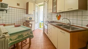 A compact kitchen with a dining table, chairs, a microwave, and a sink. - Apartament in Minori (Minori)