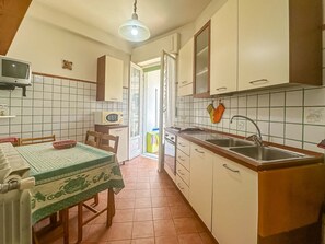 A compact kitchen with a dining table, chairs, a microwave, and a sink. - Apartament in Minori (Minori)