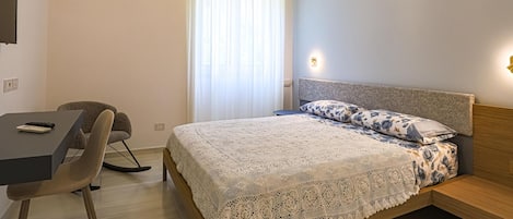 Un dormitorio con una cama, un escritorio y una silla.
