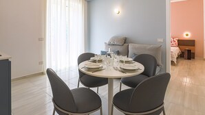 A dining area with a round table set for four, a sofa, and a bed in the background. - Donna Maria - Marialuce (Amalfi)