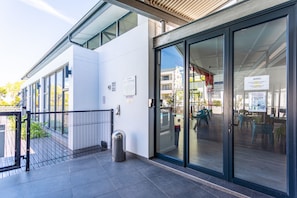 A modern building with large glass doors, a metal fence, and a trash can. - Modern 3-bed Garden Pool Gym by Ctha (Cape Town)