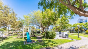 A park with a playground, a paved walkway, and a building in the background. - Modern 3-bed Garden Pool Gym by Ctha (Cape Town)