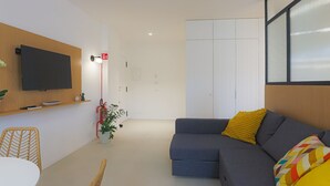 A modern living room with a flat-screen TV, a sofa with colorful cushions, a small table, and a potted plant. - Blue Elina - Amami Viaggi Collection (Salerno)