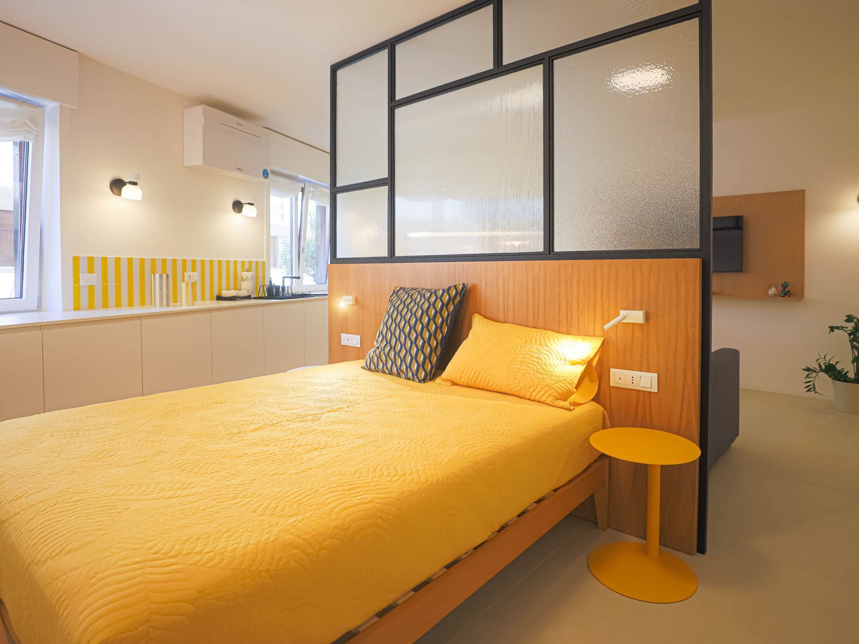 A modern bedroom with a large bed, a bedside table, and a built-in TV.