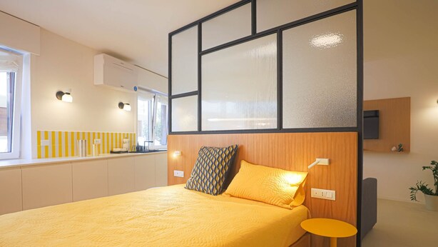 A modern bedroom with a large bed, a bedside table, and a built-in TV. - Blue Elina - Amami Viaggi Collection (Salerno)