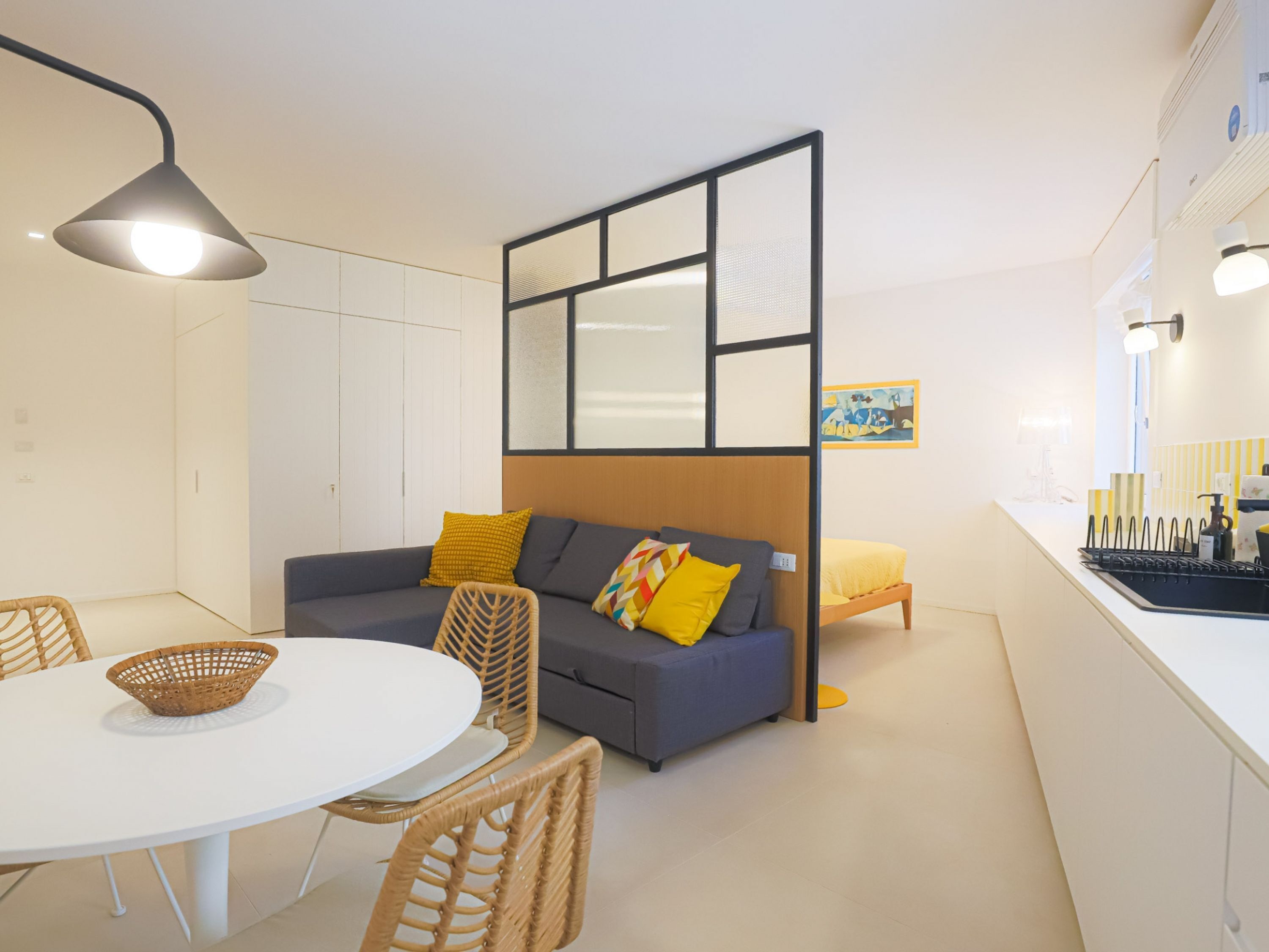 Una sala de estar moderna con sofá, sillas, una mesa de comedor y una zona de cocina.