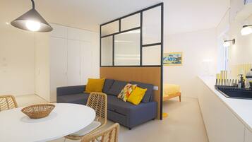 Una sala de estar moderna con sofá, sillas, una mesa de comedor y una zona de cocina.