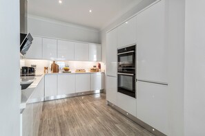 Eine moderne Küche mit weißen Schränken, Edelstahlgeräten und Holzboden.