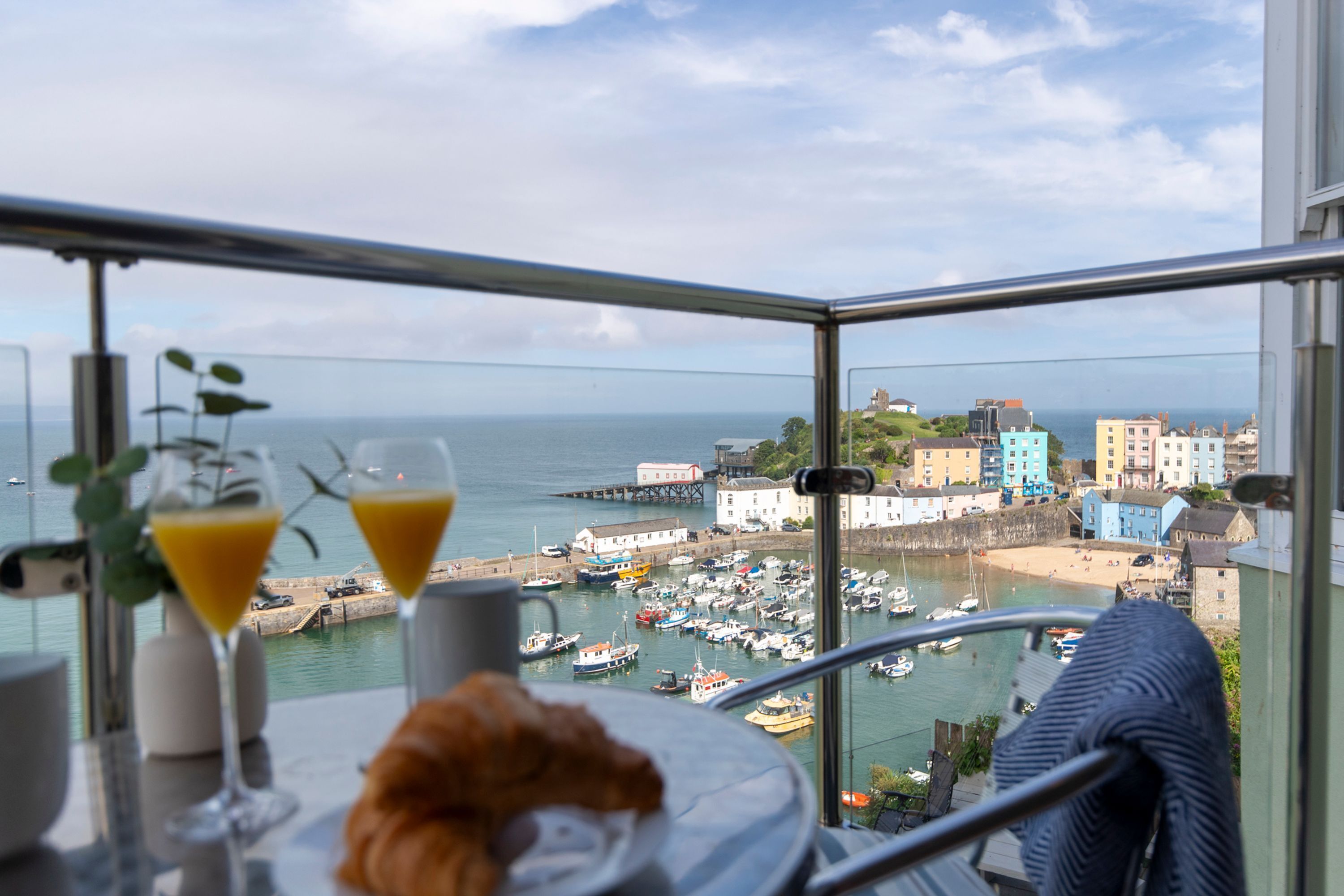 A balcony with a view of a harbor, boats, and colorful buildings.