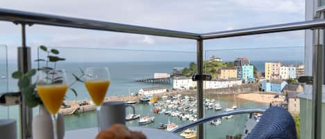 A balcony with a view of a harbor, boats, and colorful buildings.