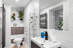 A modern bathroom with a toilet, sink, and shower area. - Hove Hideout By My Getaways (Hove)
