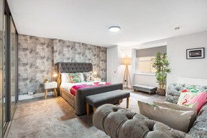 A bedroom with a bed, bedside tables, a bench, a sofa, a lamp, and a window. - Hove Hideout By My Getaways (Hove)