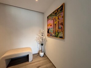 Ein Flur mit einer Bank, einem Wandbild und einem Blumentopf.