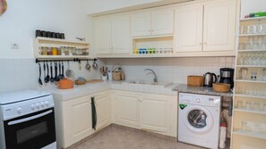A kitchen with a stove, oven, sink, and washing machine.
