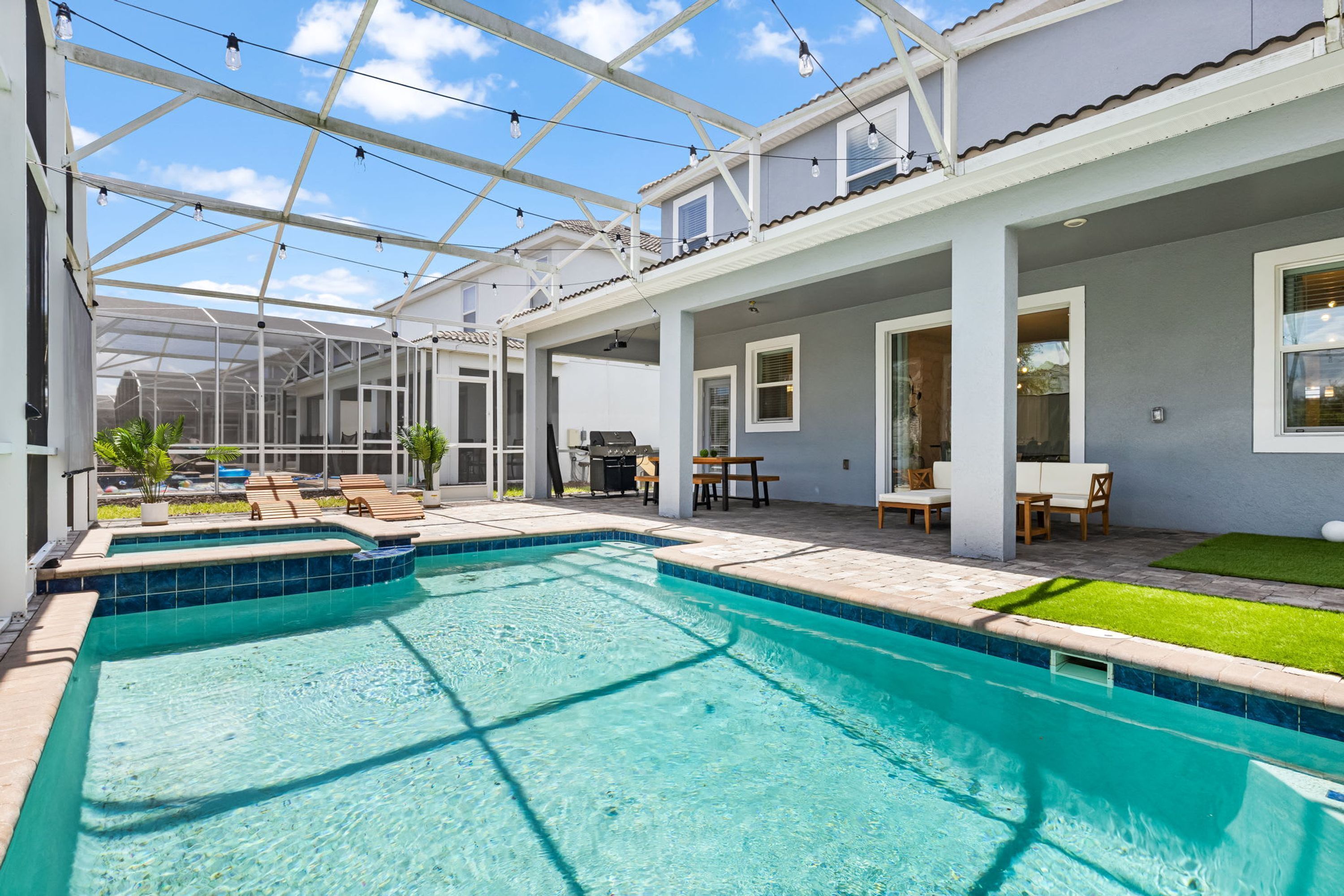 A swimming pool with a glass ceiling, outdoor seating, and a patio area.