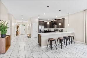 A modern kitchen with a central island, dark cabinets, and pendant lighting. - Themed 9BR Villa Pool Game Room Champions Gate (Davenport)