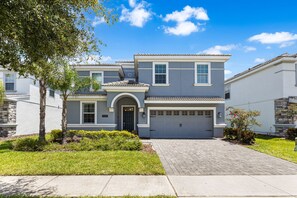 A two-story residential house with a garage, a stone facade, and a well-maintained lawn. - Themed 9BR Villa Pool Game Room Champions Gate (Davenport)
