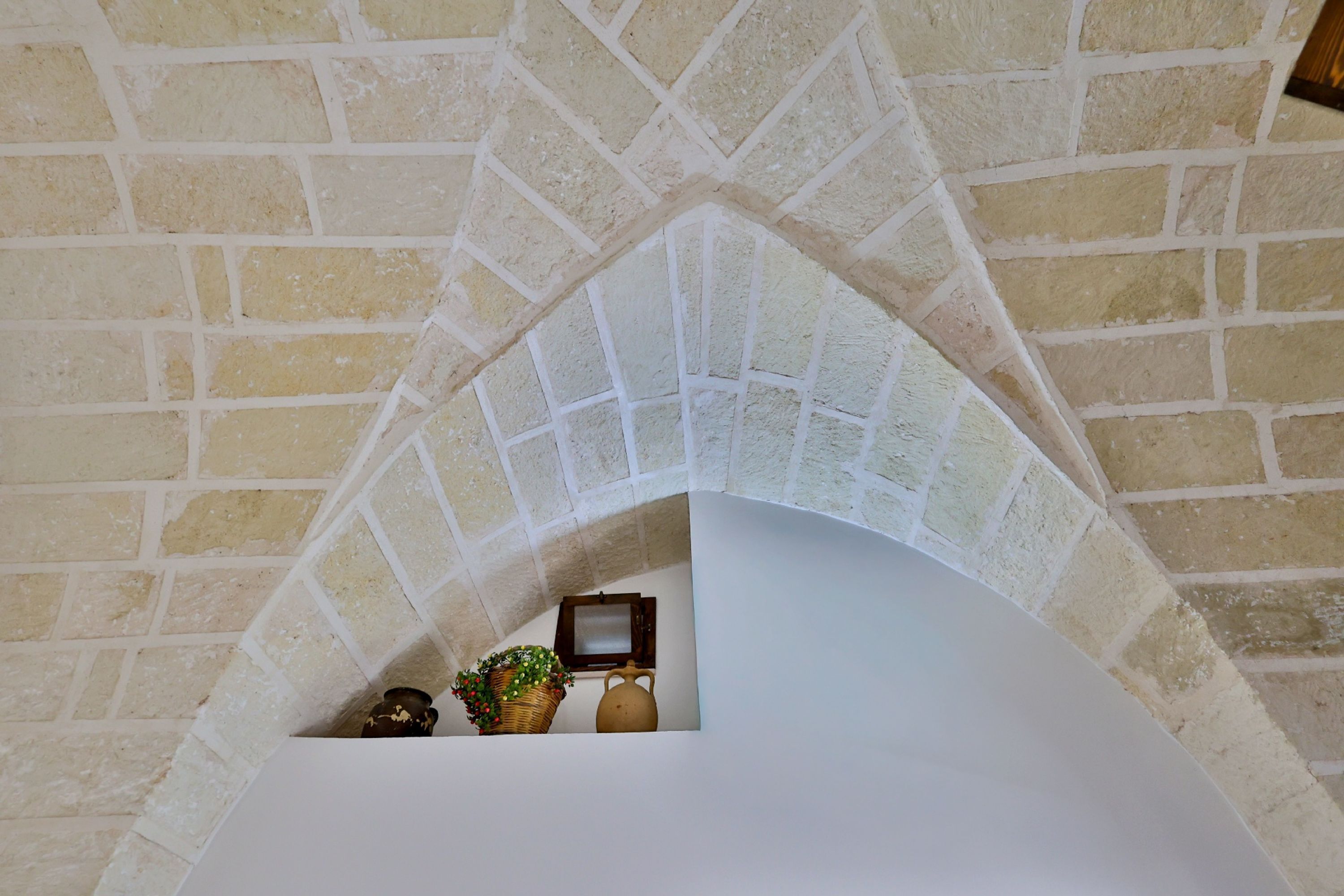 A stone archway leading to a white interior space with a small table and decorative items.